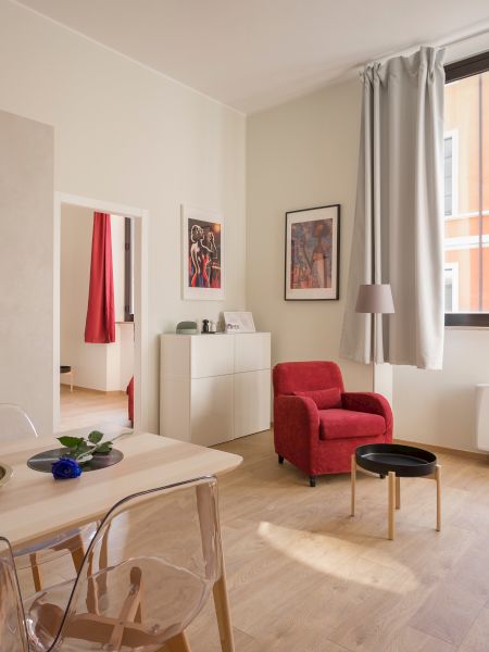 A modern living room with a dining table, red sofa, red armchair, wall art, large window, and pastel-colored cabinetry and walls ending the sentence.