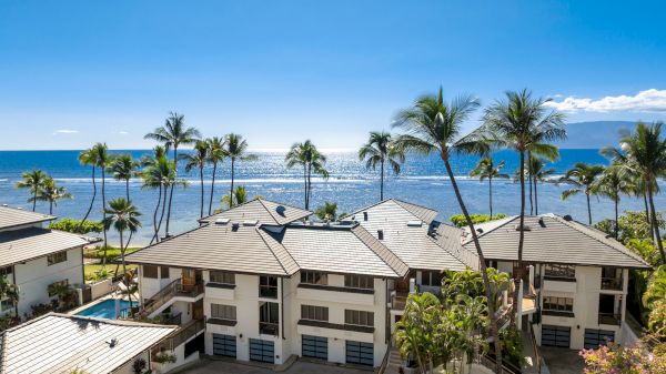 A sunny coastal scene with palm trees, beachfront condos, and a clear blue ocean beyond, under a bright sky, perfect vacation vibes.