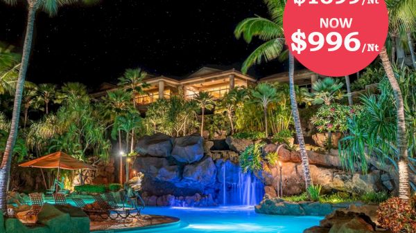 The image shows a luxurious swimming pool at night with a waterfall, surrounded by palm trees, featuring a price discount sign.