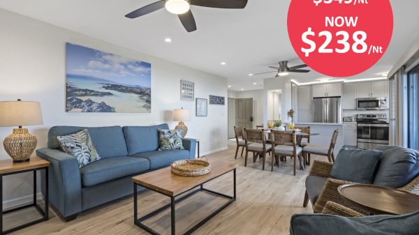 A modern living room with ceiling fans, sofas, a dining area, and a kitchen in the background. Sale: reduced from $349/night to $238/night.
