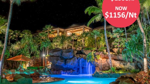 A tropical resort at night with a waterfall pool, palm trees, and a discounted rate from $1595 to $1156 per night.
