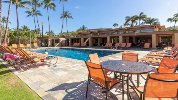 The image features a sunny pool area with lounge chairs, tables, and palm trees, creating a relaxing vacation vibe.