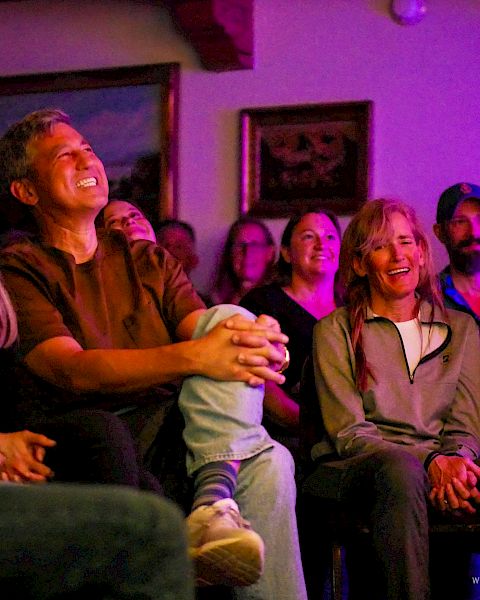 A group of people watching a show in a cozy, colorful living room; everyone smiling and laughing together.