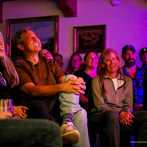 A group of people watching a show in a cozy, colorful living room; everyone smiling and laughing together.