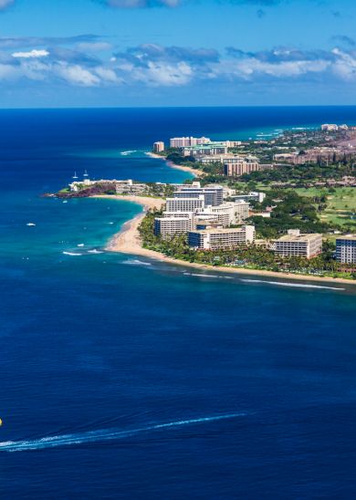 The image shows a beautiful coastal scene with clear blue waters, sandy beaches, and hotels lining the shoreline.