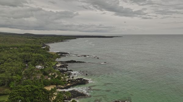 The image shows a coastal view with rocky shores, greenery, and a cloudy sky over the ocean, creating a serene atmosphere.