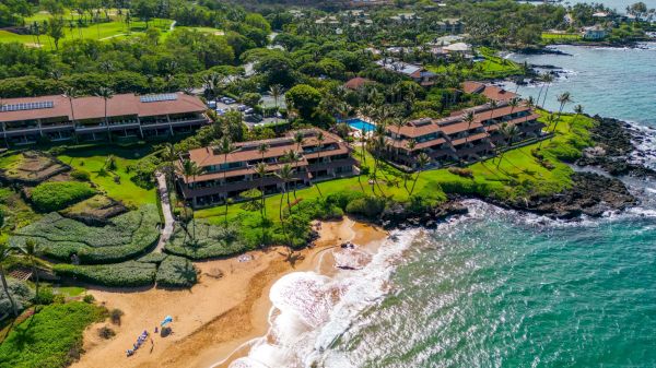 The image shows a scenic coastal view with green landscapes, beach, and buildings near the shore, capturing a serene vacation spot.
