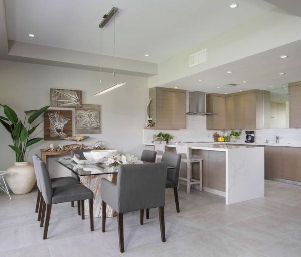The image shows a modern dining area with a table, chairs, and a sleek kitchen nearby, featuring stylish decor and greenery.