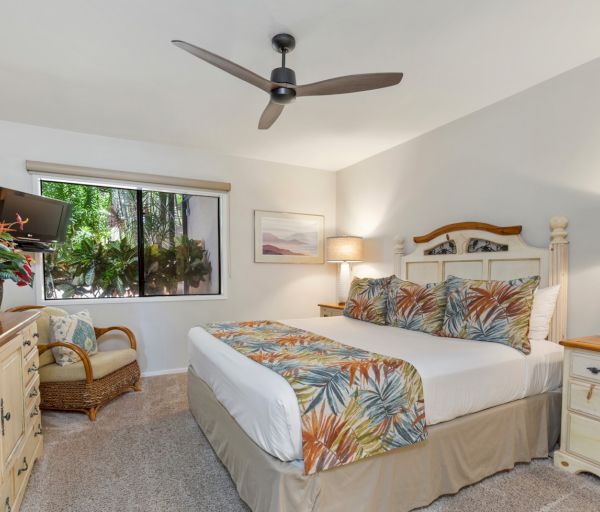 The image shows a cozy bedroom with a bed, dresser, fan, and window, featuring tropical decor and a relaxing atmosphere.