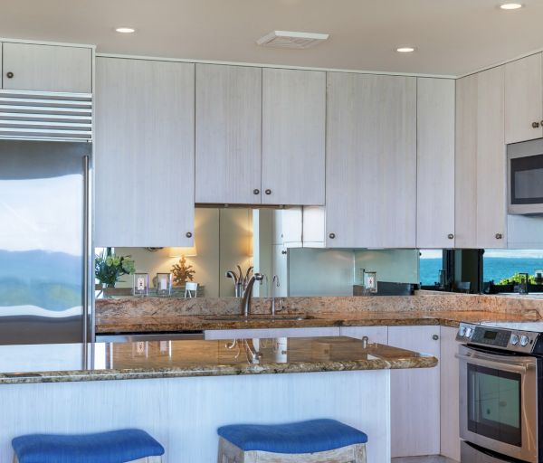 The image shows a modern kitchen with white cabinets, granite countertops, stainless appliances, and a view through the windows.