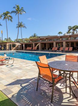 The image features a sunny pool area with lounge chairs, surrounded by palm trees and a scenic backdrop. It's quite inviting.