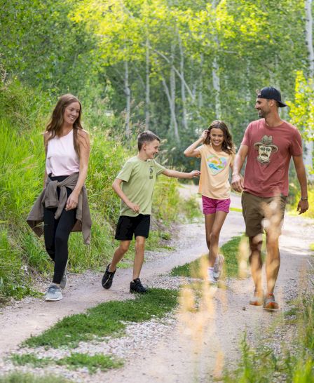 A family strolls along a path, enjoying nature and each other's company. Laughter and joy fill the air during their outing.
