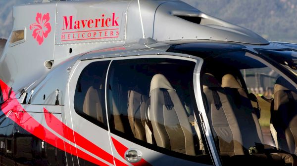 The image shows a helicopter with a logo, likely from the company "Maverick Helicopters," featuring a sleek design.