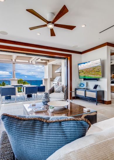 The image showcases a stylish living room with panoramic ocean views and modern furnishings, perfect for relaxation.