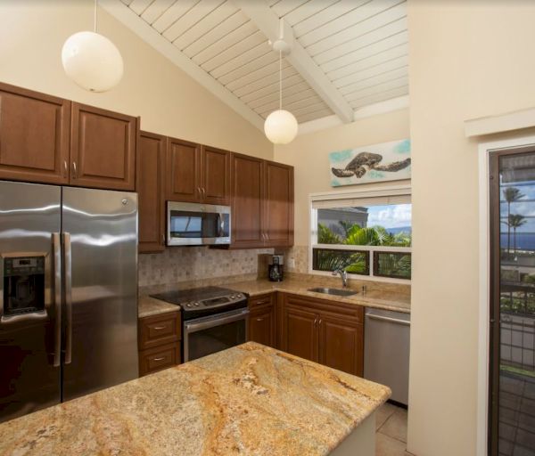 The image shows a modern kitchen with wooden cabinets, stainless steel appliances, and a scenic view through the window.