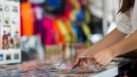 A person's hands are seen sorting through colorful printed materials on a table, with vibrant backgrounds in the background.