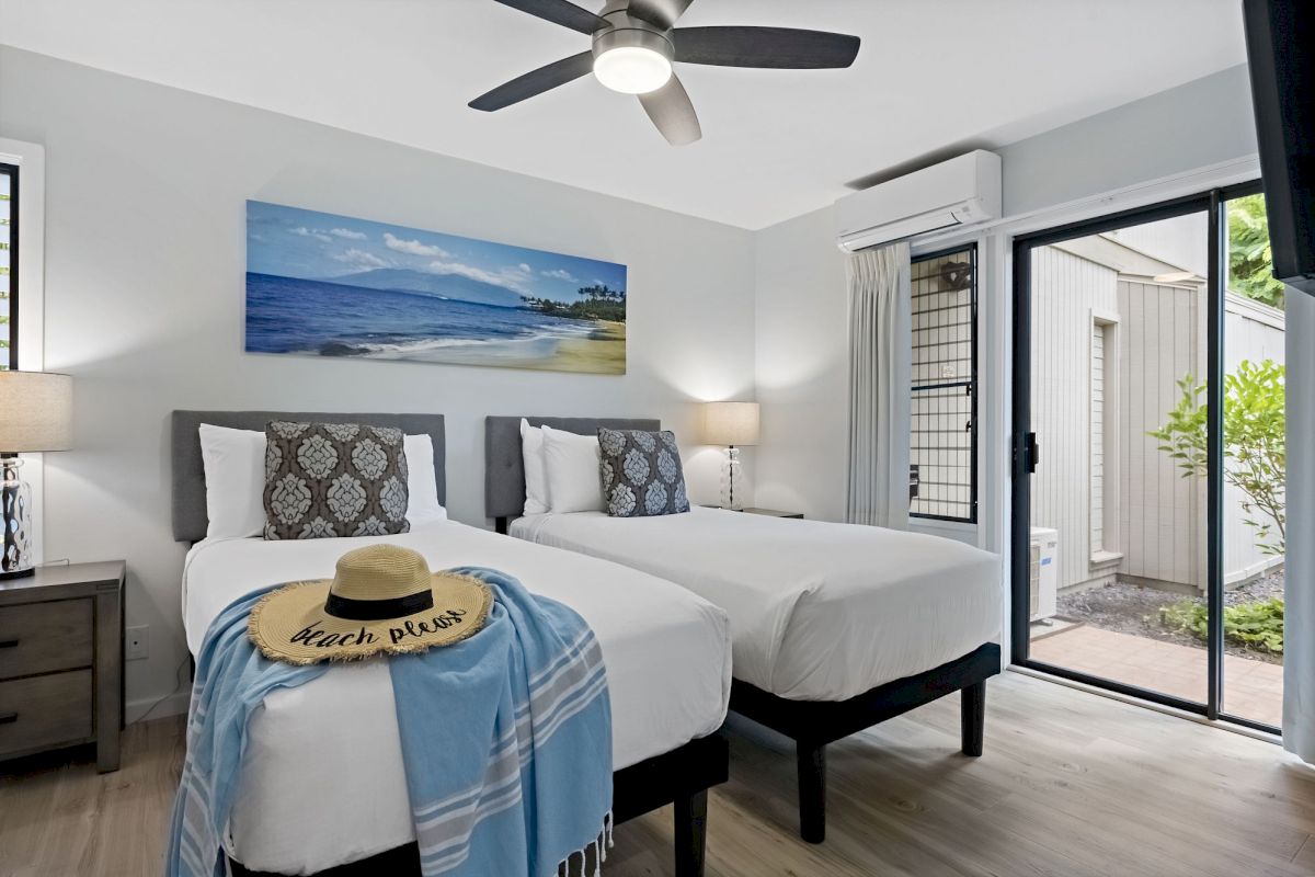 The image shows a modern bedroom with two beds, beach-themed decor, and a patio door leading outside. It's bright and inviting.