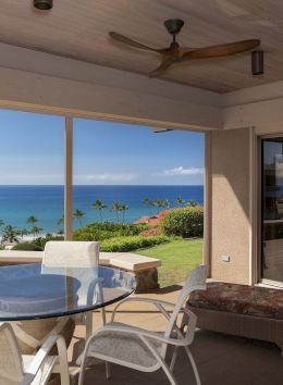 The image features a scenic patio with a glass table, chairs, and a view of a beautiful ocean coastline. It's inviting and serene.