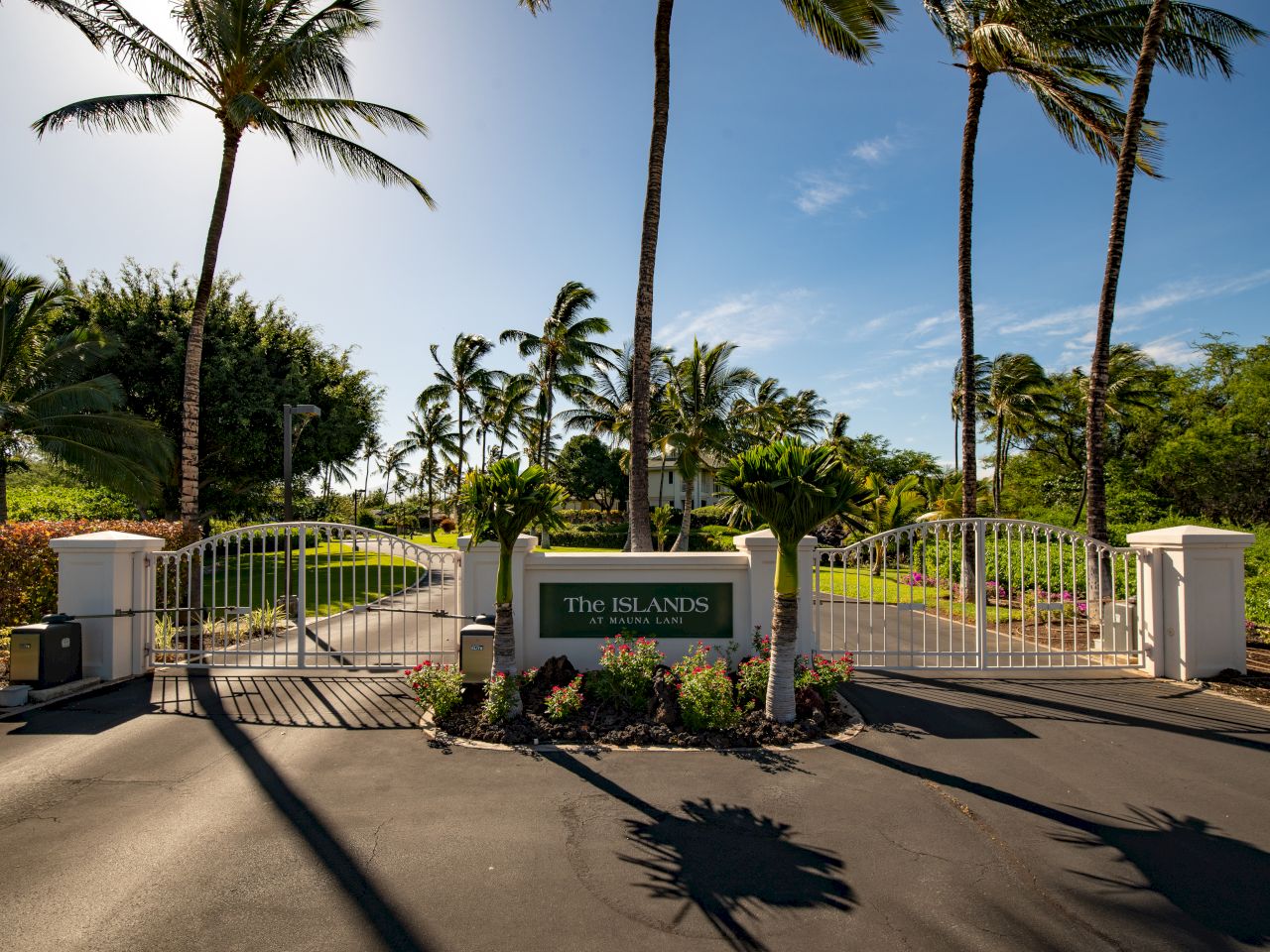 An entrance gate labeled "The Islands," surrounded by palm trees and lush greenery under a clear blue sky.