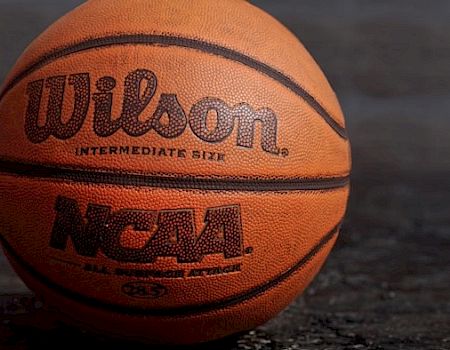 An NCAA Wilson intermediate size basketball is placed on a dark surface, showing the brand and logo in clear detail.