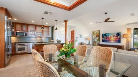 The image shows a modern open-concept living space with a kitchen, dining area, and living room, featuring stylish furniture and decor.