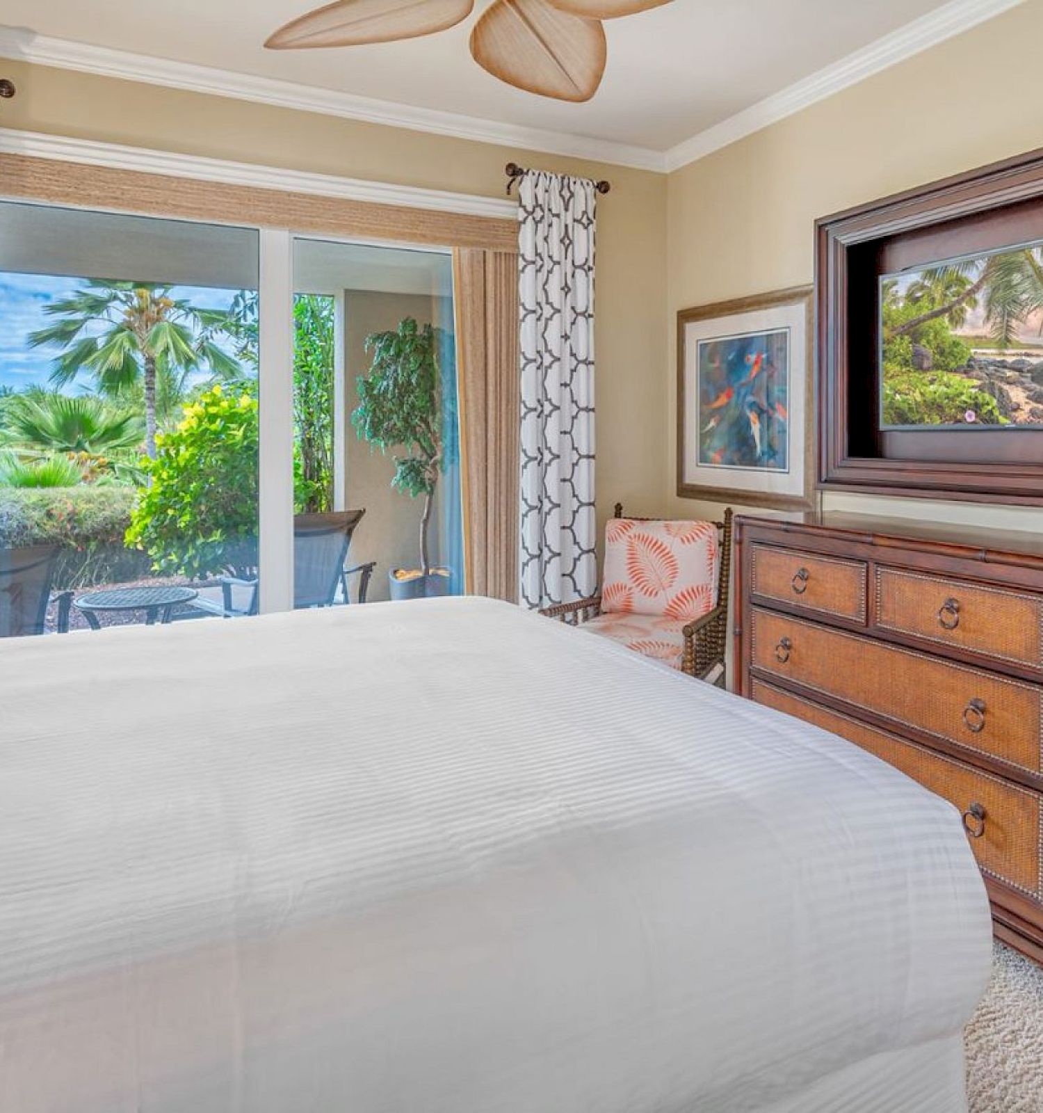 A cozy bedroom with a large bed, dresser, and window offers a view of a lush garden, and there&rsquo;s artwork on the walls.