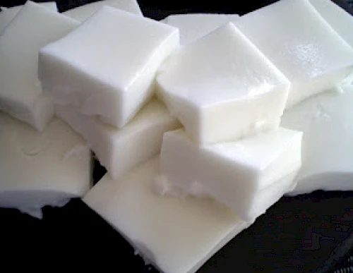 White cubed blocks, stacked on a dark plate, look like dairy butter or cheese solid pieces.
