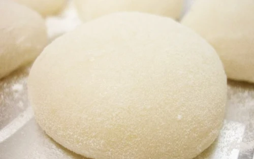 Soft, powdery-white dough balls (likely gnocchi or dumplings) on a lightly floured surface.