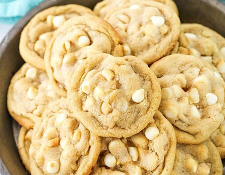 A plate of peanut butter cookies, studded with white chocolate chips, stacked invitingly and golden brown, fresh from the oven.