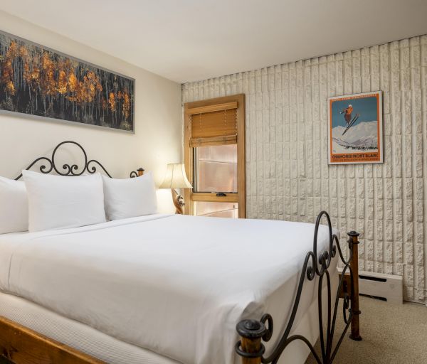 A cozy bedroom with a decorative iron bed, framed art, and textured walls, creating a warm and inviting atmosphere.