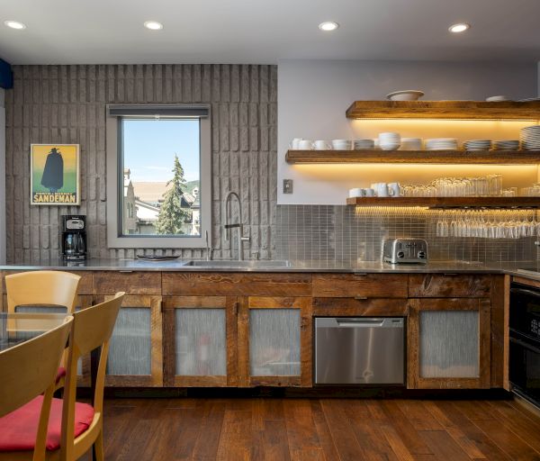 This image shows a modern kitchen with wooden cabinets, open shelves, and stainless steel appliances. A dining table and chairs are included.