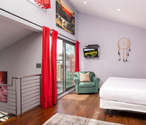 The image shows a stylish room with wooden floors, a bed, a green chair, red curtains, and wall art. It has a modern aesthetic.