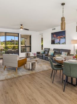 The image showcases a stylish living area with a dining table, comfortable seating, modern decor, and large windows for natural light.