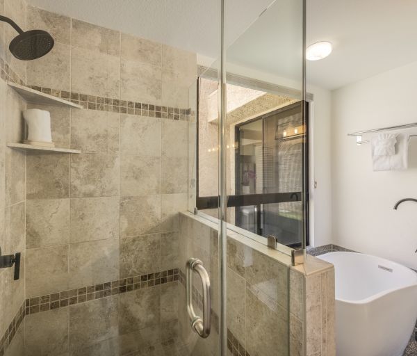 The image features a modern bathroom with a glass shower, a freestanding tub, and stylish stone tiles for a contemporary look.