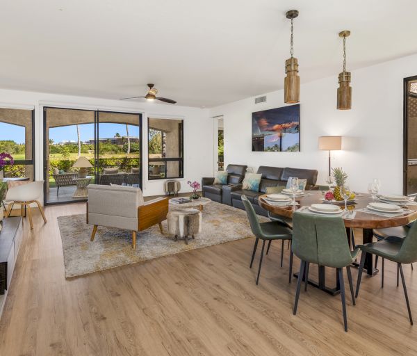 The image shows a modern living space with a dining area, comfortable seating, and large windows showcasing outdoor views.