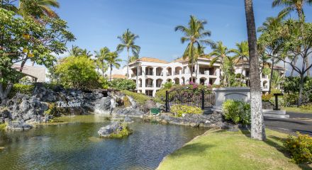 The image shows a tropical resort with palm trees, a pond, and a sign reading "The Shores," surrounded by lush greenery and bright flowers.