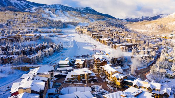 A snowy mountain resort scene, featuring chalets, ski slopes, and pine trees under a bright sky. A winter wonderland awaits.
