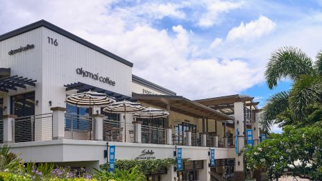 A two-story coffee shop, Diamond Coffee, with outdoor seating, umbrellas, plants, and blue skies nearby.