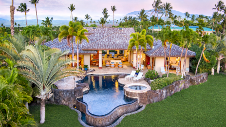 Luxurious tropical villa with a curved pool, spa, palm trees, and open-air seating, sprawling lawn, and a beachy ocean backdrop. Ending this sentence.