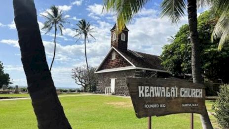 A small stone church with a wooden steeple sits among palm trees by the shore; a sign reads &ldquo;Keawala&lsquo;i Church.&rdquo;
