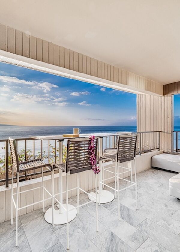 A stylish balcony with ocean views, modern seating, and a sunny lounge area overlooking the sea, perfect for relaxing in style.