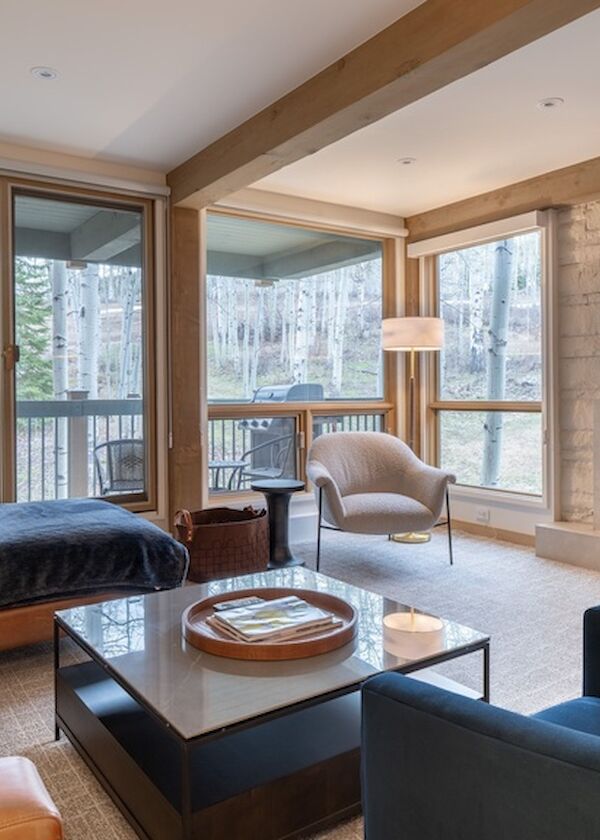 Modern living room in a high-rise condo with large windows, leather sofa, fireplace, and balcony overlooking a cityscape, cozy and bright.